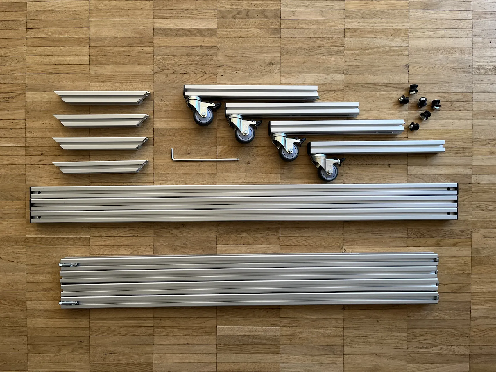 Draufsicht eines Bausatzes mit Werkzeug und einzelnen Bauelementen aus Aluminiumstangen.